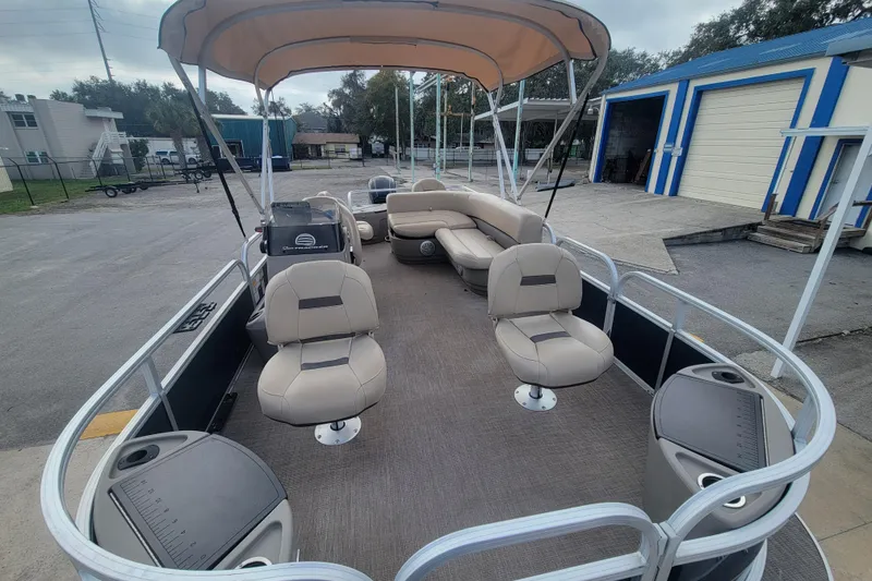 Slide: The Image of 2023 Sun Tracker Bass Buggy 18 DLX pontoon boat with seating and canopy in a parking area. - 7
