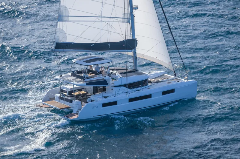 Slide: The Image of 2025 Lagoon 51 ICONIC catamaran sailing on open sea with full sails. - 23