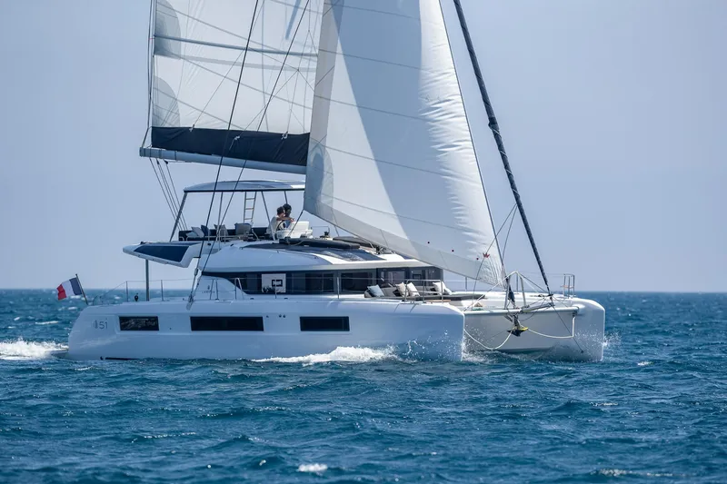 Slide: The Image of 2025 Lagoon 51 ICONIC catamaran sailing on open sea with full sails. - 3