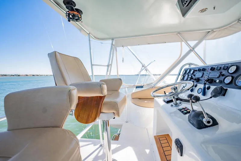 Slide: The Image of Helm of 2001 Post 42 yacht with steering wheel and control panel, overlooking serene waters. - 52