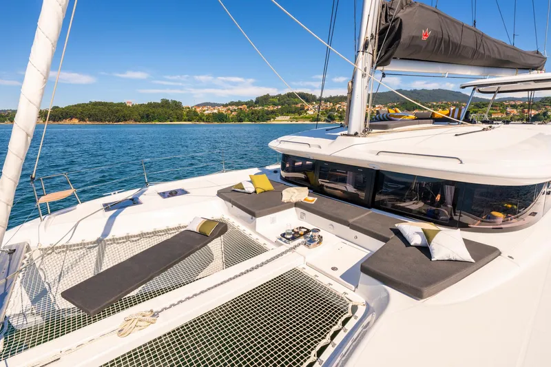 Slide: The Image of 2025 Lagoon 43 catamaran with sunbathing area, sailing on clear blue waters. - 11