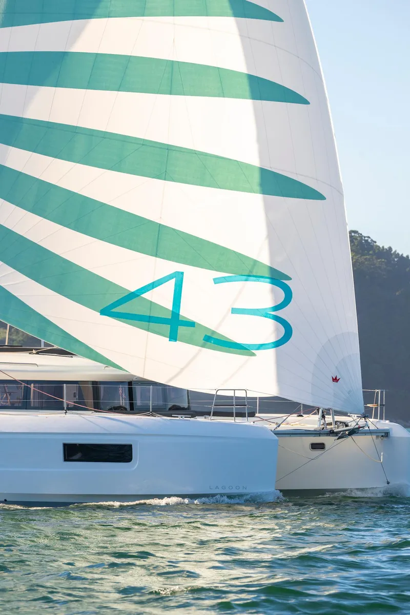Slide: The Image of 2025 Lagoon 43 catamaran sailing with green and white sails on open water. - 4