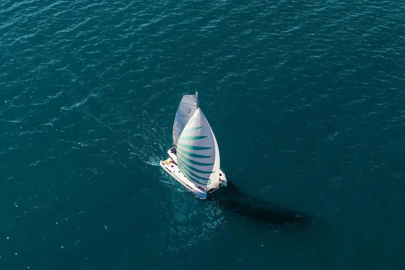 Slide: The Image of Aerial view of 2025 Lagoon 43 sailboat navigating clear blue waters. - 49