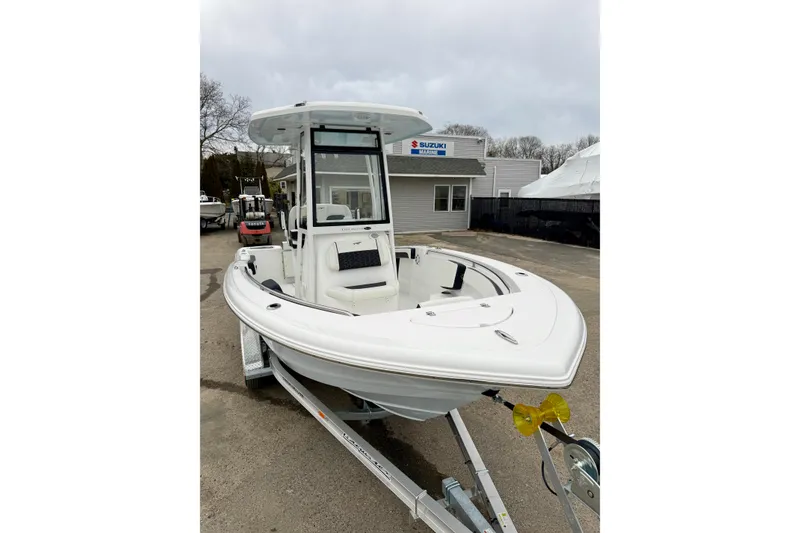 Slide: The Image of 2026 Tidewater 210 CC Adventure boat on trailer, parked outdoors near Suzuki Marine building. - 25