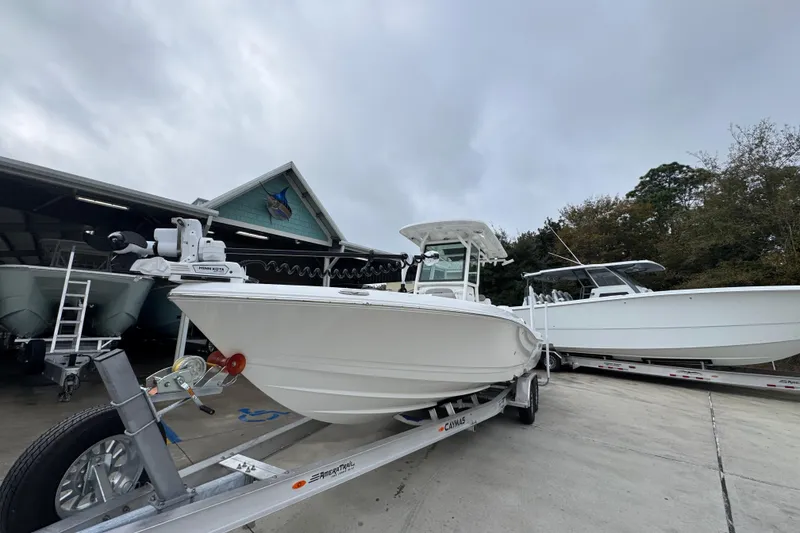Slide: The Image of 2026 Caymas 281 HB boat on trailer, parked outdoors near a boathouse. - 4