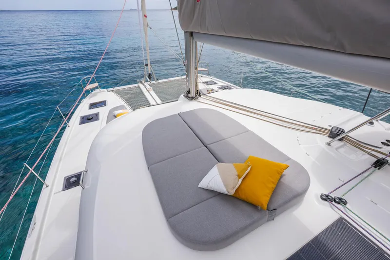 Slide: The Image of 2025 Lagoon 38 catamaran deck with cushions and pillows, overlooking serene blue waters. - 11