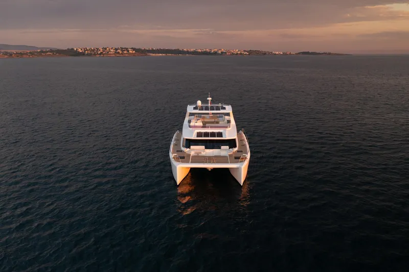 Slide: The Image of Front view of 2025 Custom Omaya 50 Power Catamaran on calm sea at sunset. - 8