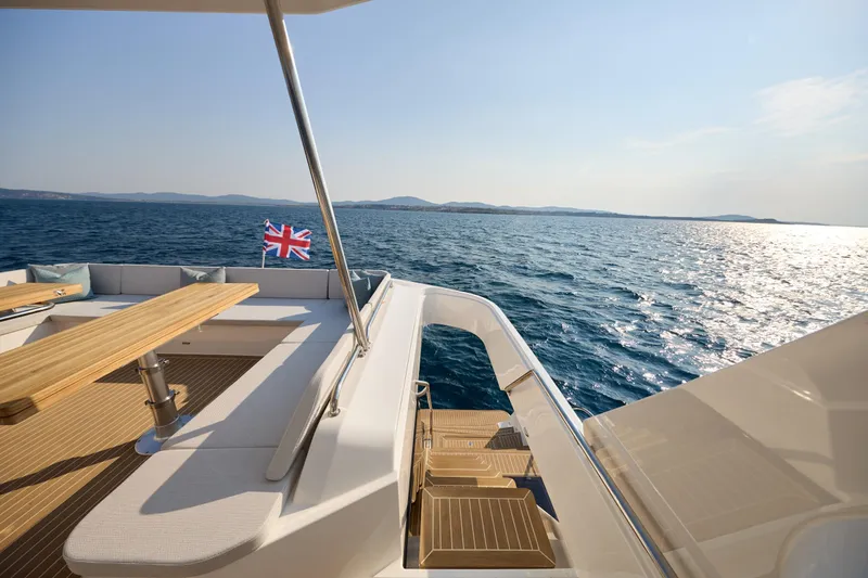 Slide: The Image of Luxurious 2025 Custom Omaya 50 Power Catamaran deck with ocean view and British flag. - 38
