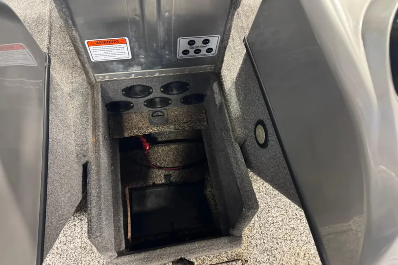 Slide: The Image of 2014 Tracker Pro Guide V-175 WT boat storage compartment with cup holders and warning label. - 14