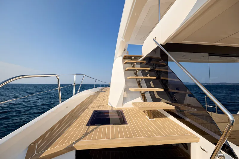 Slide: The Image of Modern Omaya 50 Power Catamaran deck with wooden stairs, ocean view, 2025 model. - 10