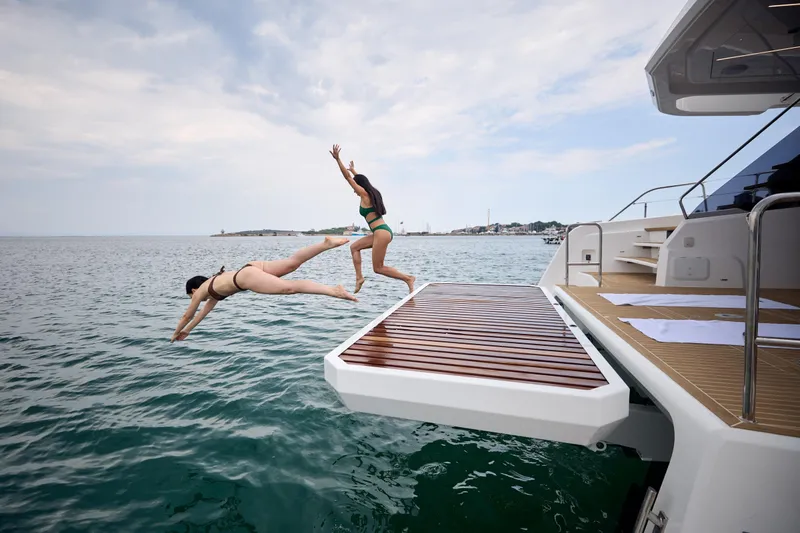 Slide: The Image of Two people diving off a 2025 Omaya 50 Power Catamaran into the ocean. - 35