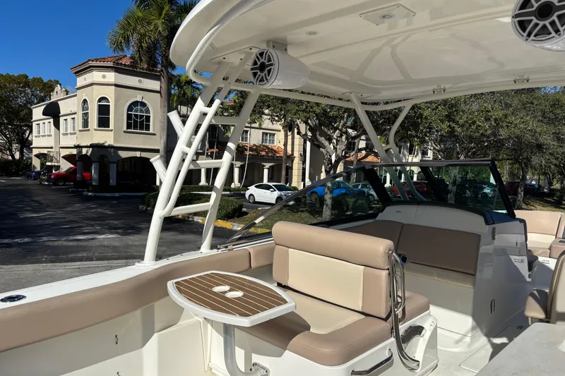 Slide: The Image of 2014 Boston Whaler 270 Vantage boat interior with seating and table, parked near residential buildings. - 14