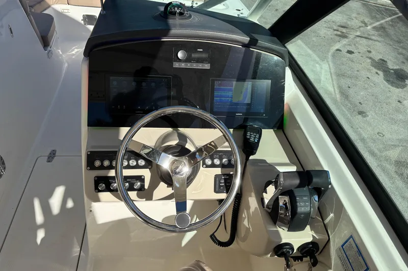 Slide: The Image of 2014 Boston Whaler 270 Vantage helm with steering wheel, controls, and navigation display. - 16