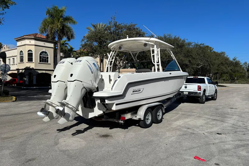 Slide: The Image of 2014 Boston Whaler 270 Vantage boat on trailer, parked near palm trees and buildings. - 4