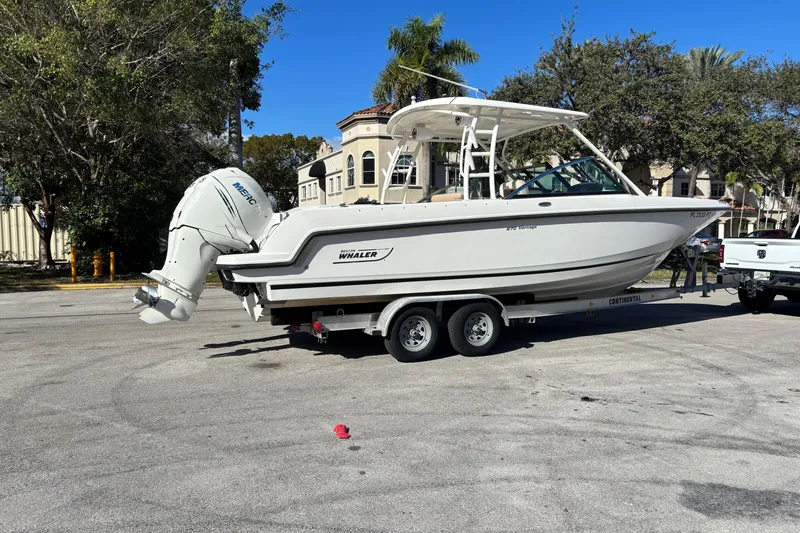 Slide: The Image of 2014 Boston Whaler 270 Vantage boat on trailer, parked outdoors with trees and buildings. - 6