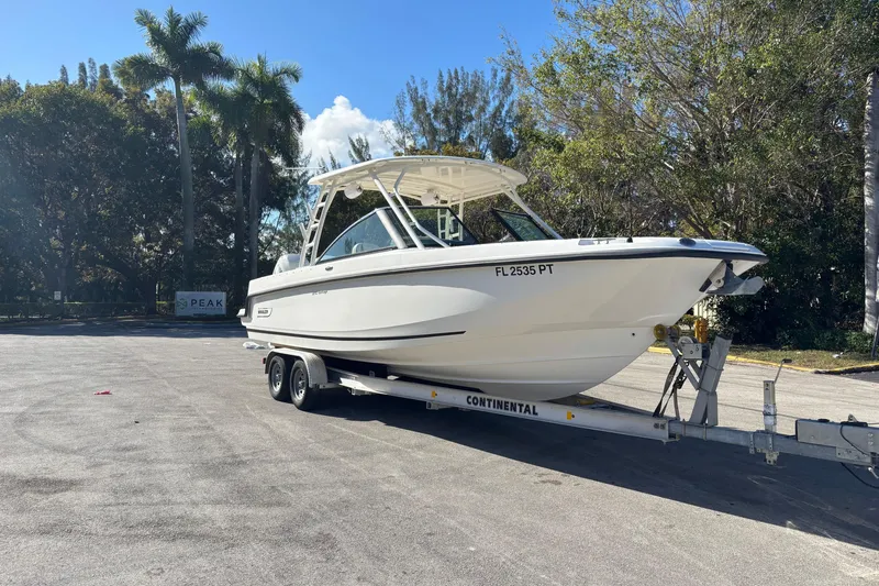 Slide: The Image of 2014 Boston Whaler 270 Vantage boat on trailer, surrounded by trees and clear sky. - 8