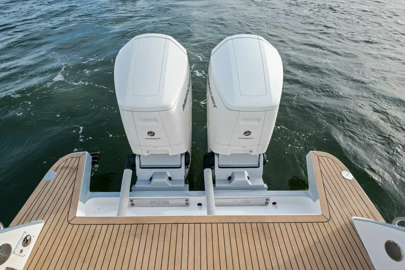 Slide: The Image of Twin outboard engines on 2025 MJM 42 boat, wooden deck, ocean background. - 30