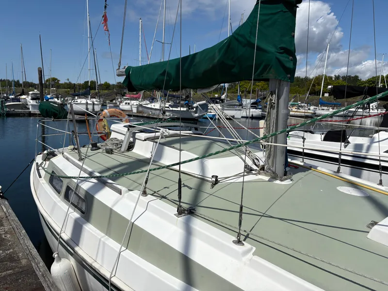 Slide: The Image of Sailboat Newport 27 S, 1981 model, docked in a marina with green sail cover. - 10