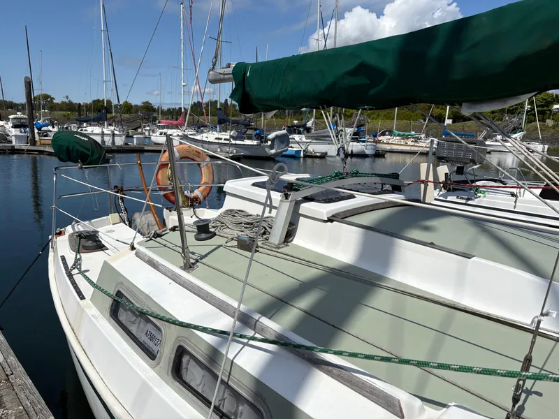 Slide: The Image of 1981 Newport 27 S sailboat docked in a marina, featuring green sail covers. - 12