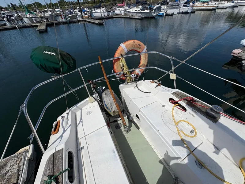 Slide: The Image of 1981 Newport 27 S sailboat docked at marina, featuring deck and safety equipment. - 20