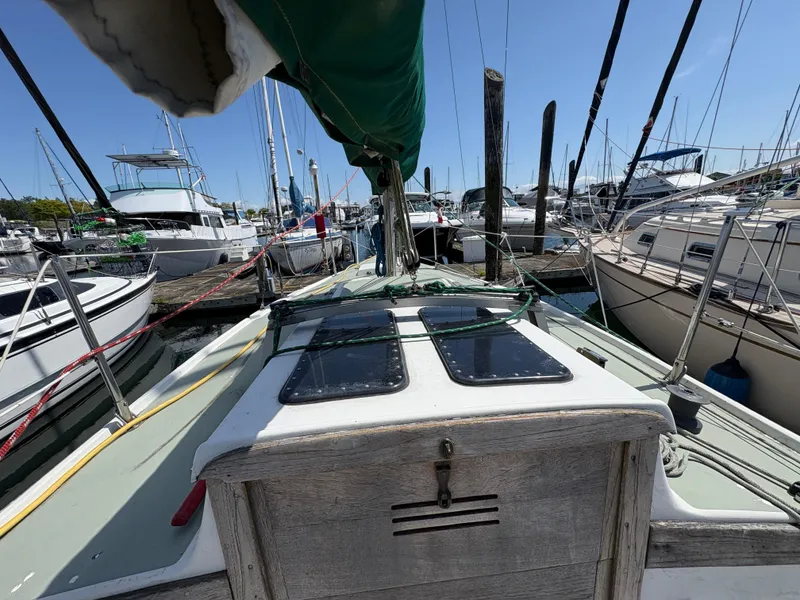 Slide: The Image of 1981 Newport 27 S sailboat docked at marina, surrounded by other boats under clear blue sky. - 23