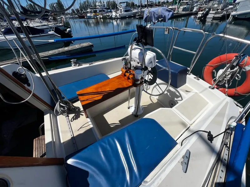 Slide: The Image of 1982 O'Day 28 sailboat cockpit with blue cushions, steering wheel, and marina background. - 16