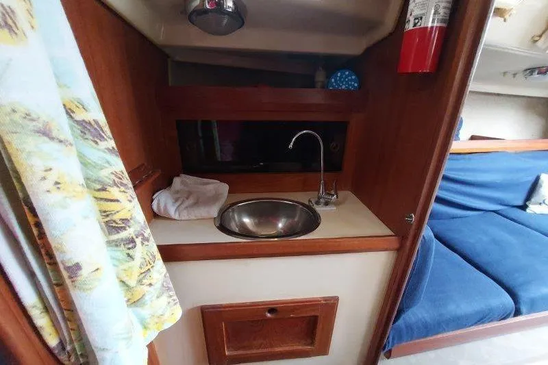 Slide: The Image of 1982 O'Day 28 sailboat interior with sink, fire extinguisher, and blue seating. - 33