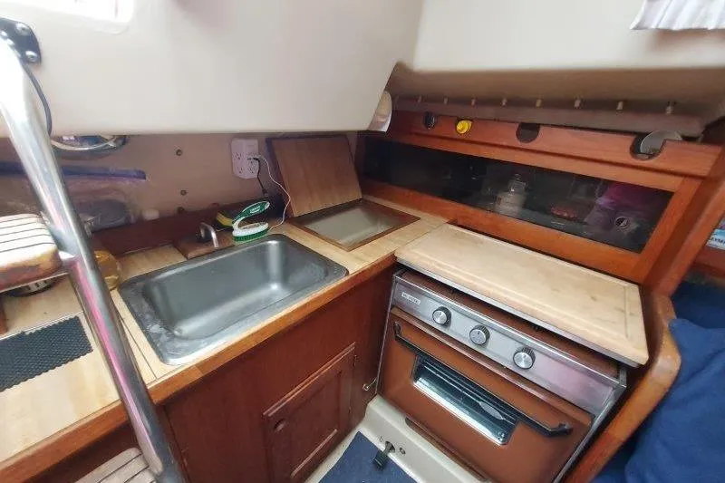 Slide: The Image of 1982 O'Day 28 sailboat galley with sink, stove, and wooden cabinetry. - 37