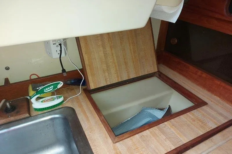 Slide: The Image of 1982 O'Day 28 sailboat interior with open storage compartment and cleaning supplies. - 40
