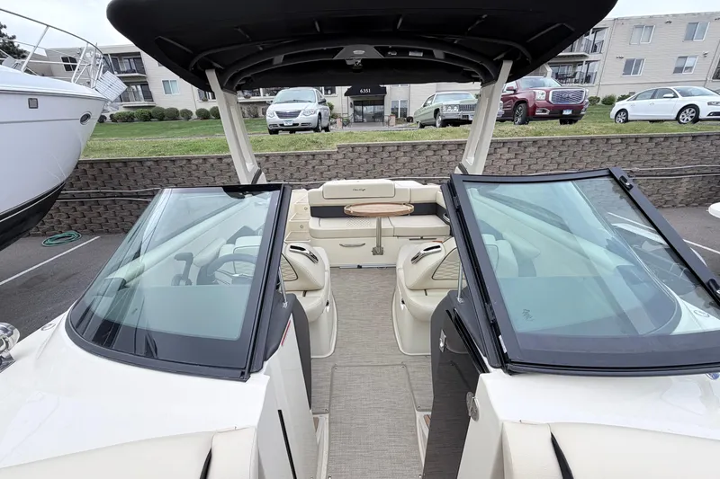 Slide: The Image of 2026 Chris-Craft Sportster 25 boat interior with seating and windshield, parked outdoors. - 23