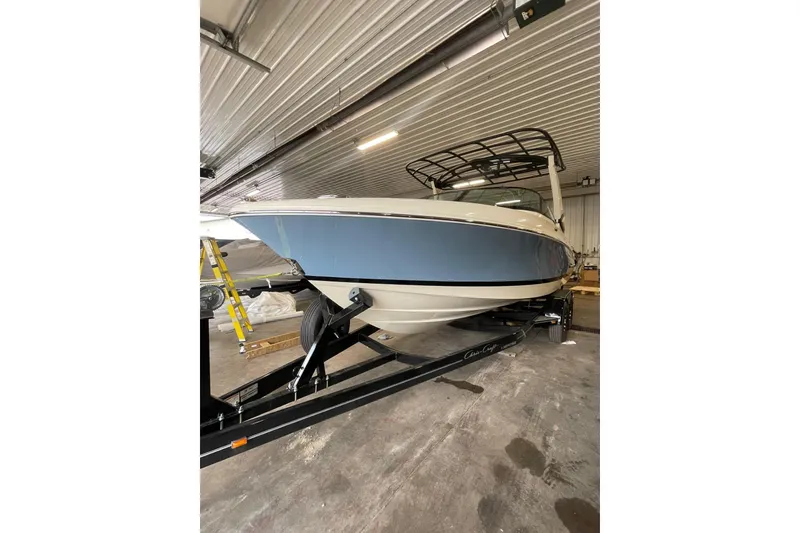 Slide: The Image of 2026 Chris-Craft Sportster 25 boat in a garage, on a trailer, with a blue hull. - 3