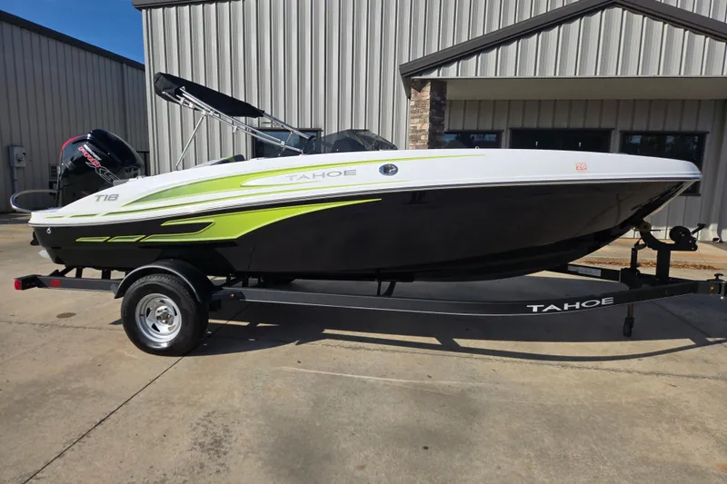 The Image of 2023 Tahoe T18 boat on trailer, black and green design, parked outside a building. - 1