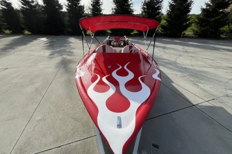 Slide: The Image of Red 1975 Weirdt Maverick boat with flame design, parked on concrete surface. - 10