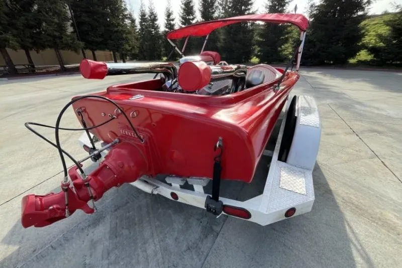 Slide: The Image of Red 1975 Weirdt Maverick boat on trailer, parked outdoors with trees in background. - 14