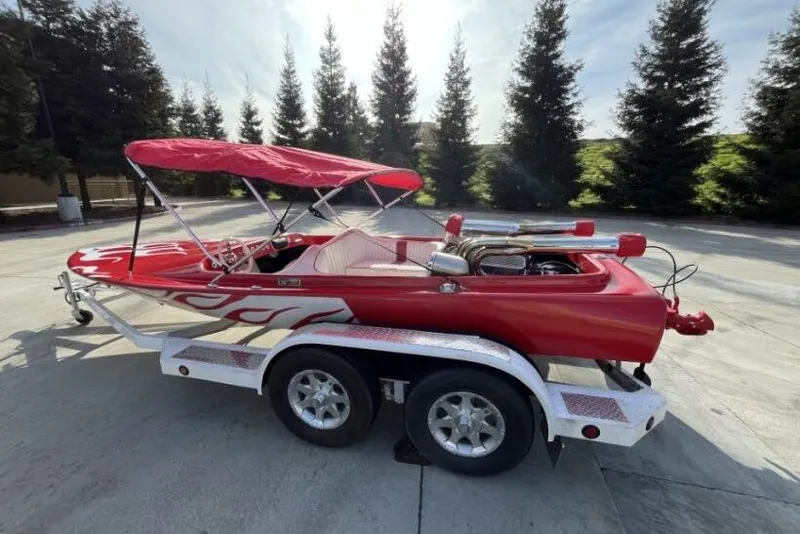 Slide: The Image of Red 1975 Weirdt Maverick speedboat on trailer with canopy, parked outdoors. - 9