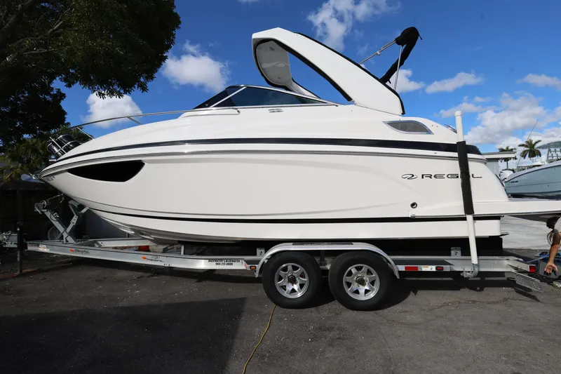 Slide: The Image of 2021 Regal 28 Express boat on trailer under blue sky. - 2