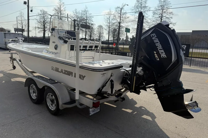 Slide: The Image of 2017 Blazer Bay 2200 boat with Evinrude engine on a trailer, parked outdoors. - 5