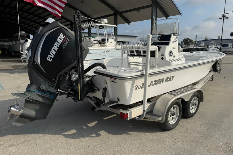 Slide: The Image of 2017 Blazer Bay 2200 boat with Evinrude engine on a trailer, parked outdoors. - 7
