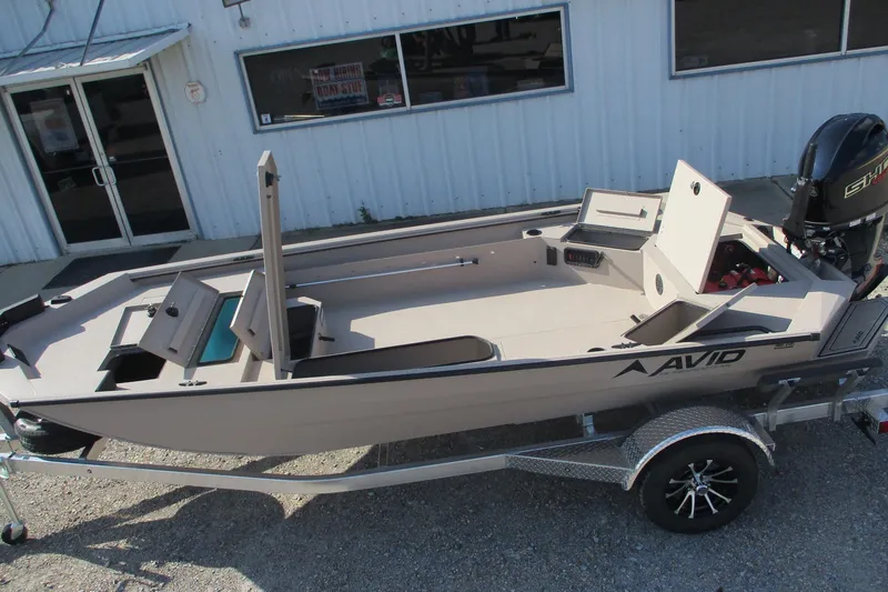 Slide: The Image of 2026 Avid 18 Commander boat on trailer, parked outside a building. - 7