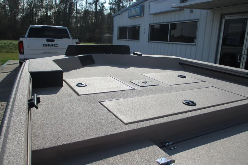 Slide: The Image of 2026 Avid 18 Commander boat deck with storage compartments, parked near a GMC truck. - 9