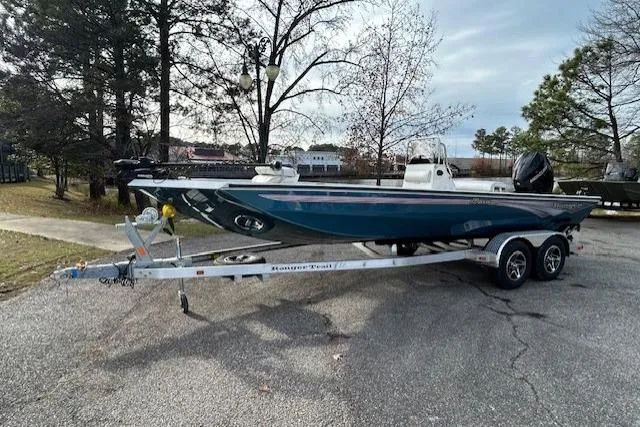 Slide: The Image of 2025 Ranger RB210 boat on trailer, parked outdoors, surrounded by trees. - 2