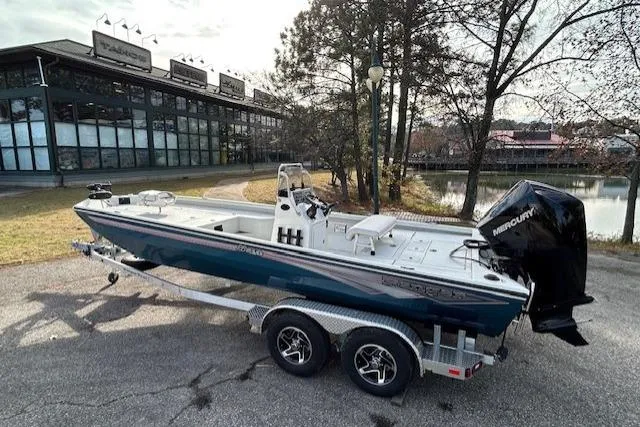 Slide: The Image of 2025 Ranger RB210 boat on trailer, parked near a modern building and trees. - 3