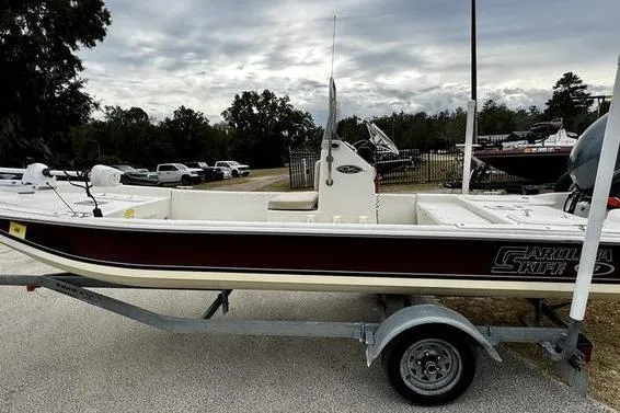 The Image of 2015 Carolina Skiff JV17CC boat on trailer, parked outdoors under cloudy sky. - 0