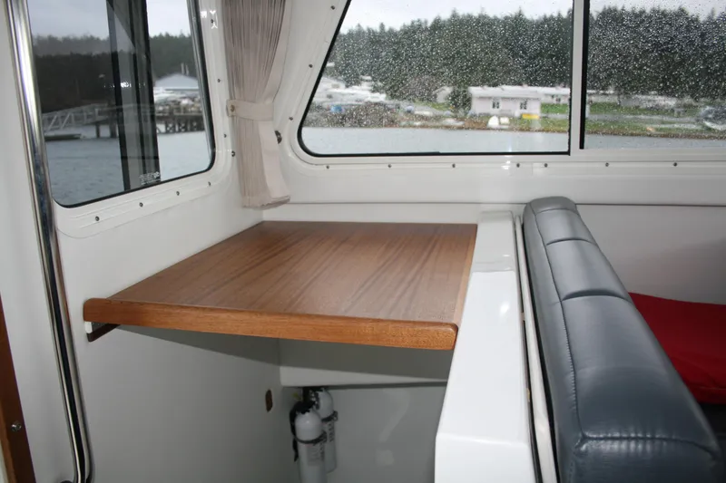 Slide: The Image of 2019 Ocean Sport Roamer 30 #117 cabin interior with gray cushions and wooden accents. - 25