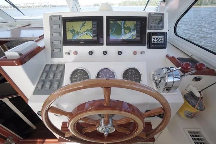 Slide: The Image of Helm of 2003 Huckins Atlantic 44 yacht with navigation screens and wooden steering wheel. - 19