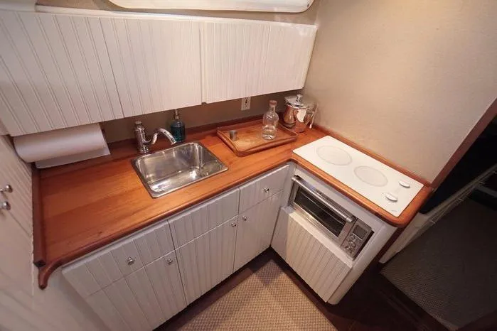 Slide: The Image of Compact galley kitchen in 2003 Huckins Atlantic 44 yacht with sink, stove, and wooden countertop. - 29