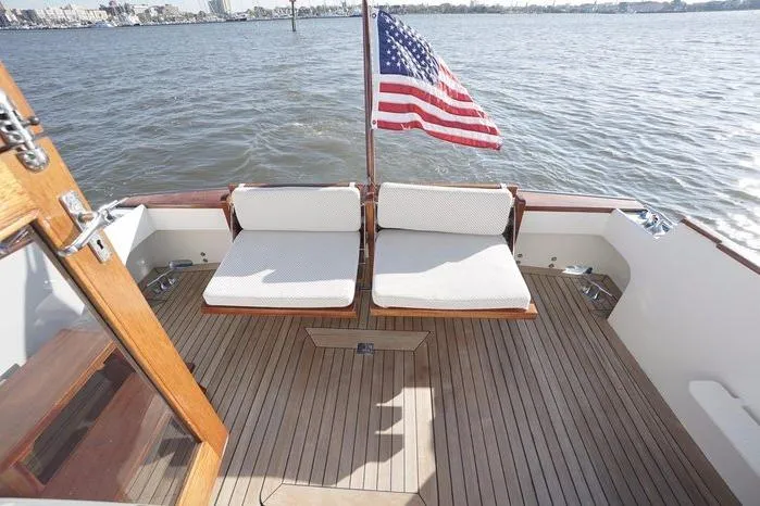 Slide: The Image of 2003 Huckins Atlantic 44 yacht deck with seating and American flag on calm water. - 6