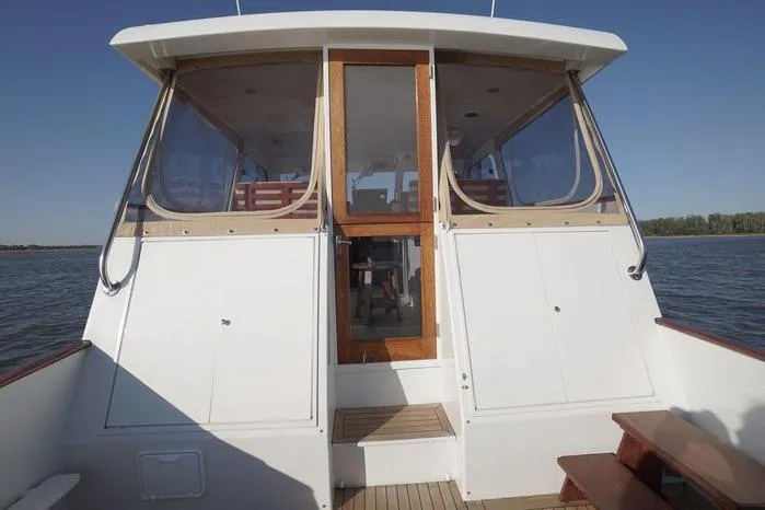 Slide: The Image of 2003 Huckins Atlantic 44 boat exterior with wooden accents and clear windows on calm water. - 7