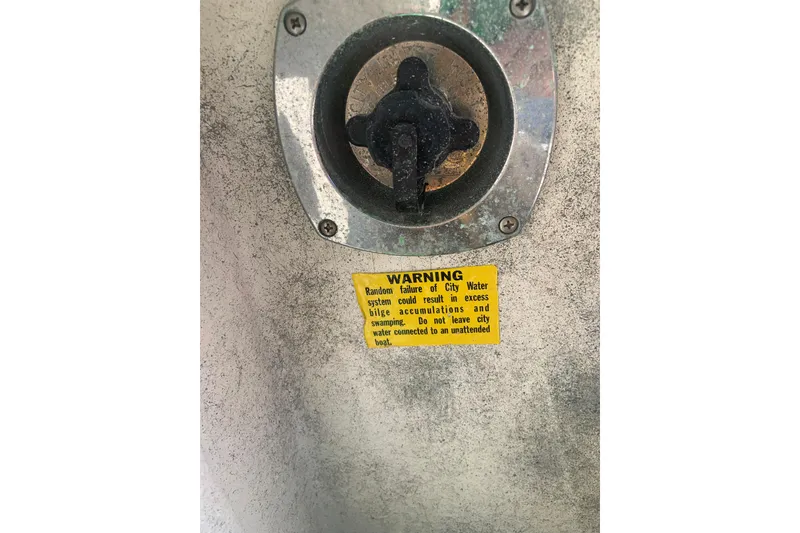 Slide: The Image of 1998 Cruisers 3375 Espirit water inlet with warning label on metal surface. - 27