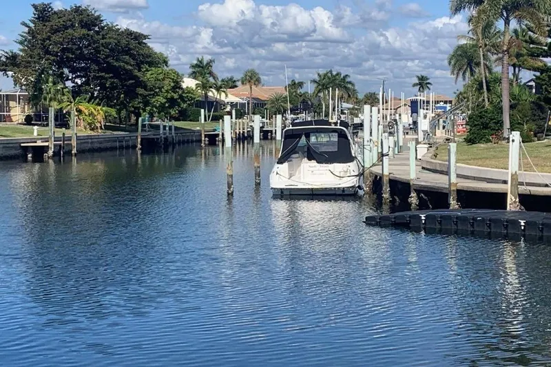 Slide: The Image of 1998 Cruisers 3375 Esprit docked in a scenic canal with palm trees. - 3